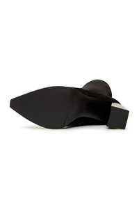 Zwarte suède enkellaars met een spitse neus en een contrasterende blokhak. De zool is glad met een gestructureerd patroon voor grip.