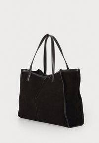 Sac fourre-tout en daim noir avec des anses en cuir lisse et structuré. Présente un design de couture asymétrique unique et un corps large et spacieux.