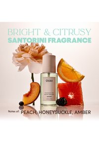 Flacon de brume parfumée étiqueté OUAI Santorini avec une tranche de pêche, une fleur de chèvrefeuille, un pamplemousse, une mûre et une tranche d'orange sur une surface réfléchissante.