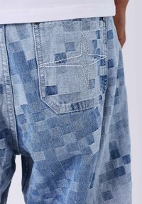 Pantaloni blu denim con motivo a scacchi e tasca posteriore con ricamo a stella bianca. Include dettagli di cuciture a contrasto.