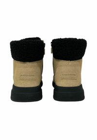 Tan ankle boots with a black, textured fur collar. Features a smooth suede upper and a rubber sole. Logo visible on the back.