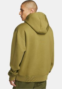Olijfgroene hoodie met een ontspannen pasvorm, ribgebreide boorden en onderrand. Gemaakt van zacht materiaal met een gladde textuur en minimale details.