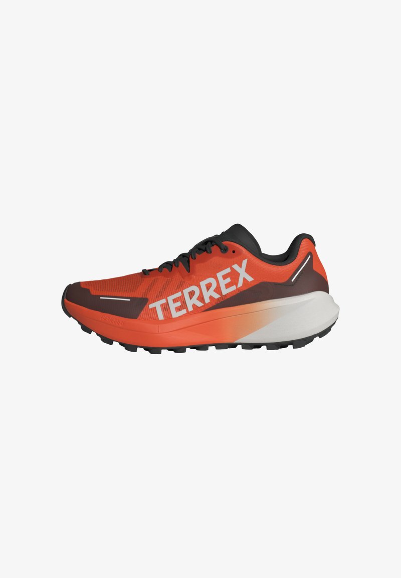 Juoksukengät, joissa on punainen verkko-osa, mustat yksityiskohdat ja valkoinen "TERREX" -brändäys. Varustettu paksulla pohjalla, jossa on loivasti siirtyvä väri oranssista valkoiseen.