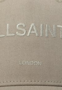 Gorra beige con texto bordado en relieve de color beige claro "ALLSAINTS" y "LONDRES". Textura de tela suave con detalles de costura a lo largo del ala.