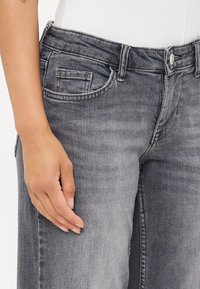 Grå denimjeans med en klassisk femficksdesign, lätt blekning och en knappstängning i midjan. Texturerat tyg med en mjuk finish.