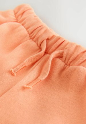 Sportske hlače boje breskve koje imaju mekanu teksturu, elastični pojas sa naboranim materijalom i detalj s vezicama za podešavanje pristajanja.