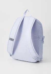 Lichtblauwe rugzak met een gevoerde achterkant en schouderbanden, uitgerust met een zijritszak en een klein logoaccent. Zacht, duurzaam materiaal.