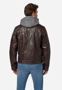 Braune Lederjacke mit grauem Kapuzenfutter. Verfügt über ein strukturiertes Design, Druckknöpfe und eine strukturierte Lederoberfläche. Lässige Passform.