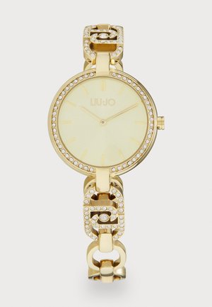 Goldene Armbanduhr mit runder Zifferblatt, hellem Ziffernblatt und eingraviertem Kristallbesatz. Das Armband besteht aus ineinandergreifenden Gliedern und dekorativen Akzenten.