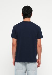 Marineblå bomulds t-shirt med klassisk rund hals og korte ærmer, lige kant og afslappet pasform. Enkelt og ensfarvet design.