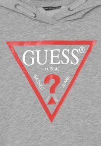 Felpa grigia con un logo triangolare rosso, con la scritta "GUESS U.S.A." e il testo "WASHED JEANS" con i numeri 1201 e 1203 all'interno.