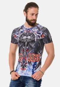 Kurzärmliges Grafik-T-Shirt mit einem auffälligen schwarz-weißen Adlerdesign, bunten, kunstvollen Akzenten und einer figurnahen Passform auf blauem Hintergrund.