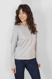 Světle šedý kardigan s dlouhým rukávem, kulatým výstřihem, zapínáním na knoflíky, měkkou texturou a přiléhavým střihem, kombinovaný s tmavě modrými džíny.