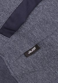 Donkerblauwe textuurstof met een klein zwart label met "J&JOY" erop. Het ontwerp bevat een effen marine accent, wat het geheel versterkt.