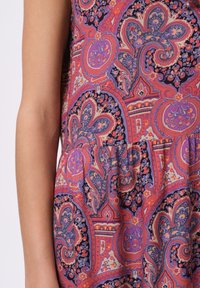 Wielokolorowa tkanina w wzór paisley w odcieniach różu, fioletu i niebieskiego; miękka tekstura z falbaną na końcach.