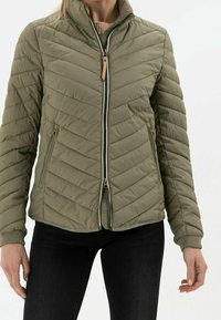 Olivgrüne Steppjacke mit Zickzack-Steppmuster, Reißverschluss und Seitentaschen. Verfügt über gerippte Bündchen und einen hohen Kragen.