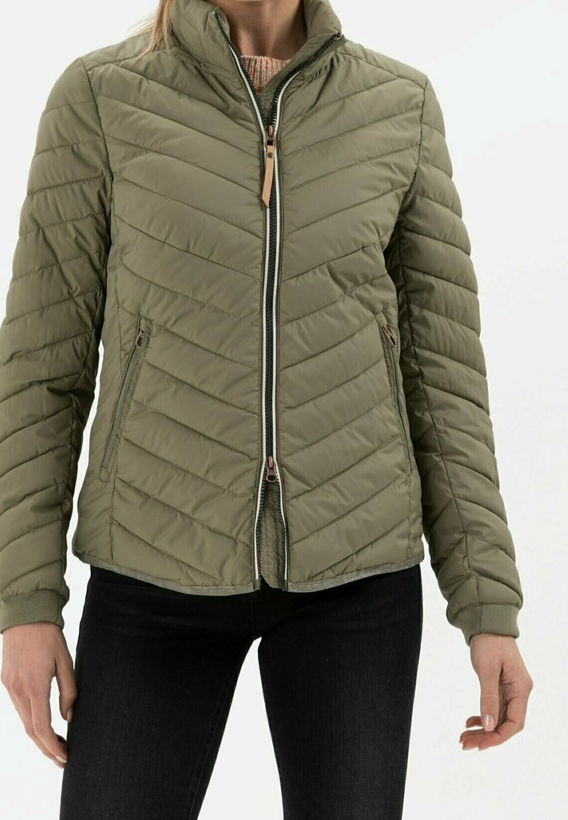 Olivgrüne Steppjacke mit Zickzack-Steppmuster, Reißverschluss und Seitentaschen. Verfügt über gerippte Bündchen und einen hohen Kragen.