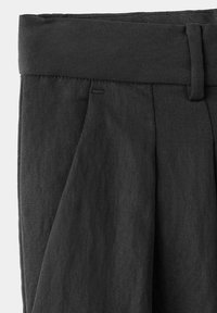 Pantalon noir taille haute avec plis, large ceinture, passant de ceinture et poche latérale visible sur le devant gauche.
