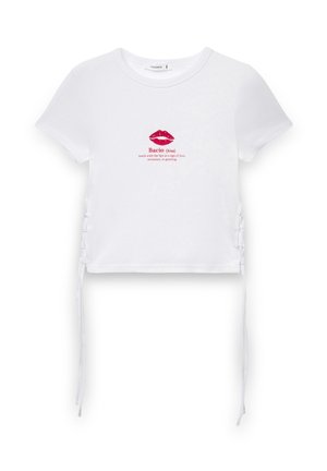 Top corto in cotone bianco a maniche corte con grafica di un rossetto rosa e testo "Bacio". Presenta lacci laterali regolabili per una vestibilità perfetta.
