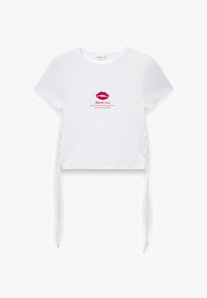Top corto in cotone bianco a maniche corte con grafica di un rossetto rosa e testo "Bacio". Presenta lacci laterali regolabili per una vestibilità perfetta.