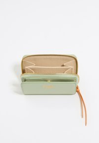 Portafoglio verde con texture, dotato di zip dorata e logo, caratterizzato da più scomparti per carte e un dettaglio arancione sul tirazip. Interno beige.
