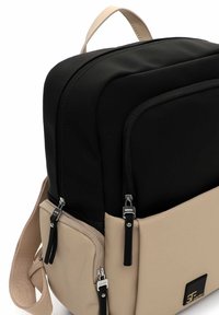 Černý a béžový batoh s hladkým povrchem, dvěma kapsami na zip, nastavitelným popruhem a elegantními černými kovovými doplňky.