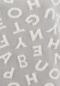 Lettere bianche in rilievo sparse casualmente su uno sfondo di tessuto grigio texture.