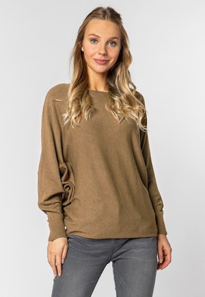 Brauner, lockerer Pullover mit Rundhalsausschnitt und langen Ärmeln, kombiniert mit grauen Jeans, vor einem neutralen Hintergrund. Glatte Textur.