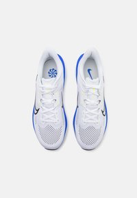 Witte sportschoenen met blauwe accenten, bovenwerk van mesh, zwart logo en gele details. Vetersluiting met een gewatteerde kraag en tong.
