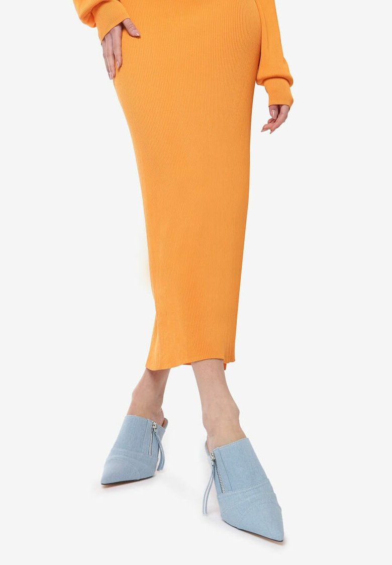 Mule azzurro chiaro con punta a osso, realizzato in un tessuto testurizzato, dotato di zipper laterale e suola flessibile, abbinato a un vestito arancione a coste.