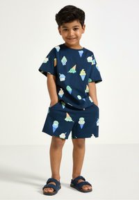 Mörkblå bomull t-shirt och shorts-set med ett färgglatt mönster av glasskulor. Har korta ärmar och fickor på shortsen.
