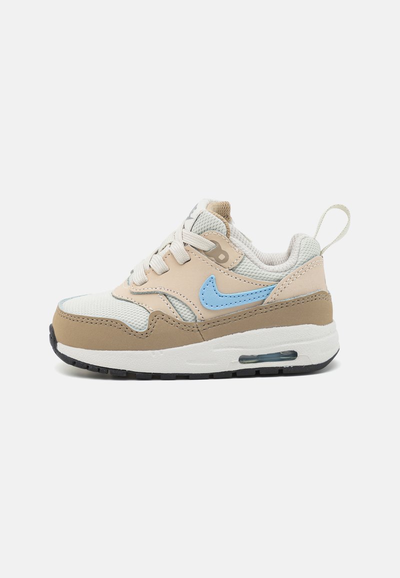 Jasno brązowe i blado niebieskie sneakersy Nike z siateczkowymi i skórzanymi elementami, z okrągłym noskiem, sznurowaniem oraz widoczną jednostką powietrzną w podeszwie.