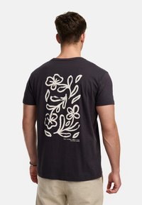 Dunkelgraues Baumwoll-T-Shirt mit einem weißen Blumenmuster auf der Rückseite, runder Ausschnitt und kurzen Ärmeln. Unten steht der Text "WILD FLOWER VIBES/1993."