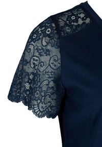 Camiseta azul marino con cortas mangas de encaje con patrones florales y bordes en forma de ondas, contrastando con un cuerpo de algodón suave.