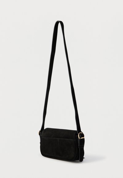 Μαύρη τσάντα ώμου από σουέτ με ρυθμιζόμενο λουρί και αγκράφα σε χρυσό τόνο, τοποθετημένη σε απλό λευκό φόντο.