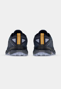 Bežecké topánky s námorní modrou vrchnou časťou, zelenými akcentami a reflexným logom. Obsahujú žltý prúžok na päte a textúrovanú šedú podrážku.