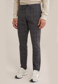 Grijze geblokte broek met een slim fit, voorzien van een gladde voorkant, zijzakken en een subtiele textuur, gecombineerd met witte en grijze sneakers.