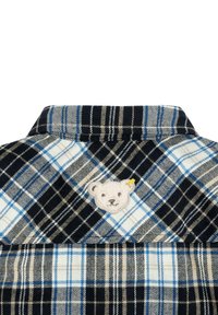 Camicia di flanella con un motivo a quadri in blu navy, blu e crema. Include un'applicazione a forma di orso sul colletto per un tocco di dettaglio in più.