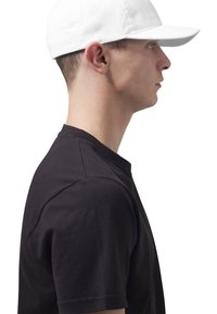 Hvid baseballkasket med en buet skygge, båret af en person i en sort rundhalset t-shirt, set fra siden, der fremhæver kaskettes enkle design.