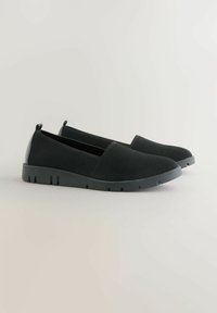Pari di scarpe nere slip-on con tessuto in mesh traspirante, suole in gomma spessa e linguette sul tallone, esposte su uno sfondo semplice chiaro.