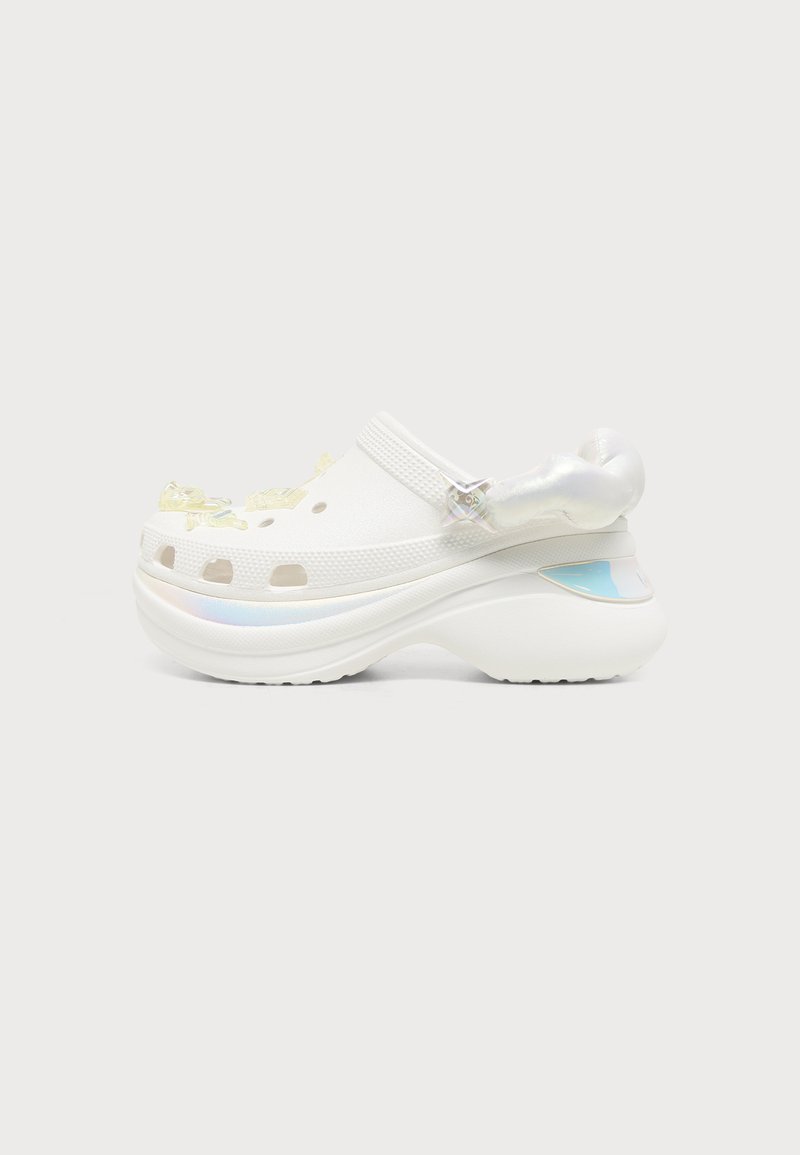 Sabot à plateforme blanc avec dessus perforé, bride arrière ajustable et semelle épaisse avec talon incurvé et accents irisés.