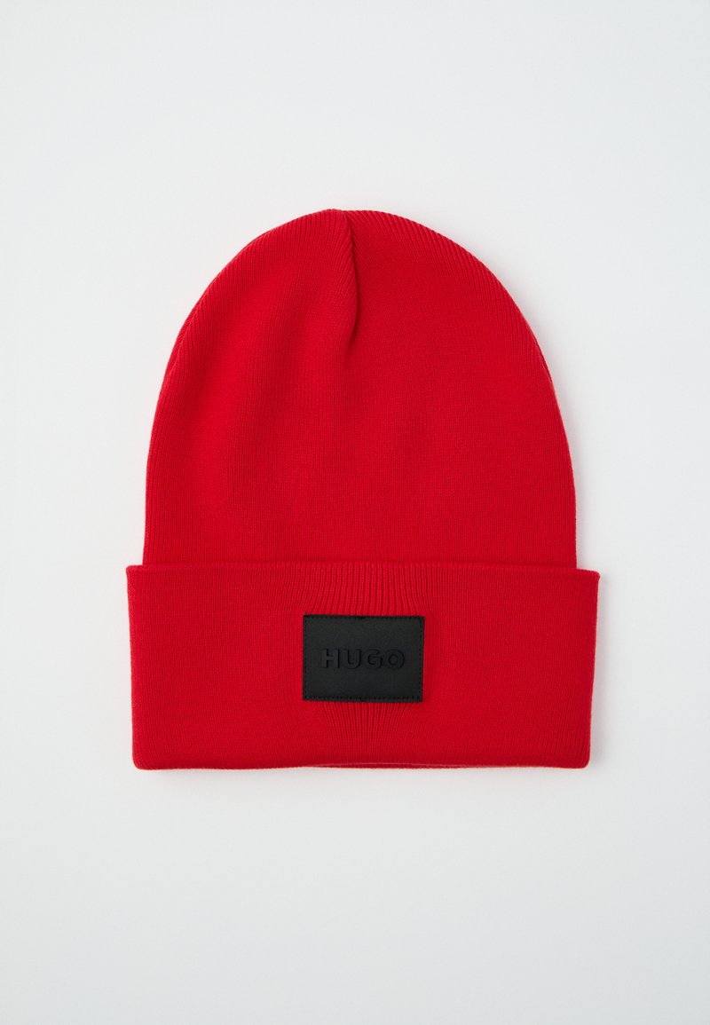 Red knitted beanie with a folded cuff and a black rectangular patch displaying "HUGO." Smooth texture, simple design, and no additional embellishments.