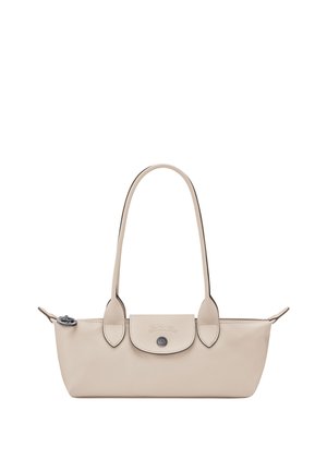 Small beige leather handbag with long handles, front flap pocket with button, and zipper closure on top.