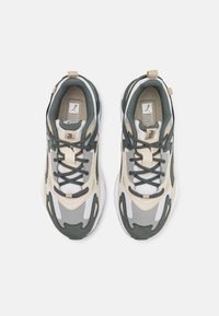 Sport shoes featuring a mixed material upper in green, beige, and grey, with a textured sole, lace-up closure, and padded collar.