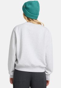 Grijze katoenen sweatshirt met ribbels bij de mouwen en hem, met een ronde hals. Draag deze met donkere broeken en een teal gebreide muts.