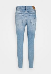 Jeans skinny de mezclilla azul claro con cintura alta, que cuentan con dos bolsillos traseros y una etiqueta de cuero marrón en la cinturilla.