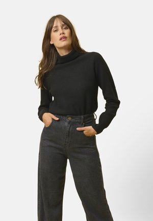 Zwarte geribbelde coltrui gecombineerd met hoge taille donkere jeans. De stof lijkt zacht met lange mouwen en een aansluitend ontwerp.