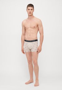 Boxeres de algodão bege com uma cinta preta com o logótipo "Polo Ralph Lauren" e pequenos padrões bordados por todo o lado.