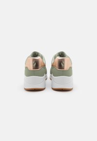 Green athletic shoes featuring a textured upper, metallic rose gold heel accents, white soles, and a cushioned interior for comfort.