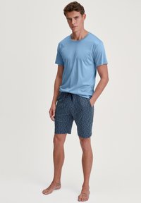 Lichtblauw T-shirt met korte mouwen gecombineerd met donkerblauwe shorts met een geometrisch patroon, voorzien van een elastische tailleband met trekkoord.